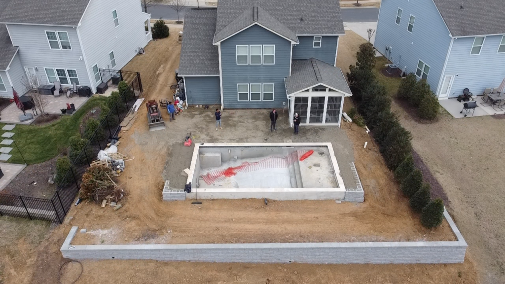 Aerial view of a new block retaining wall around a backyard pool build