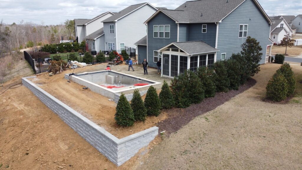 Block retaining wall with new shrubs beside a pool build